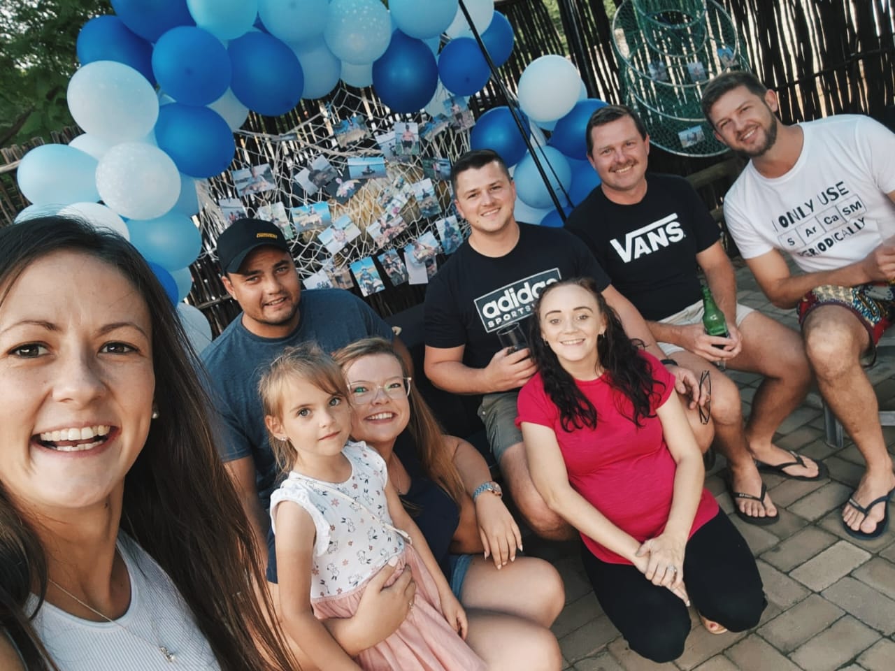 Angelo and friends taking a selfie under the blue balloon arch