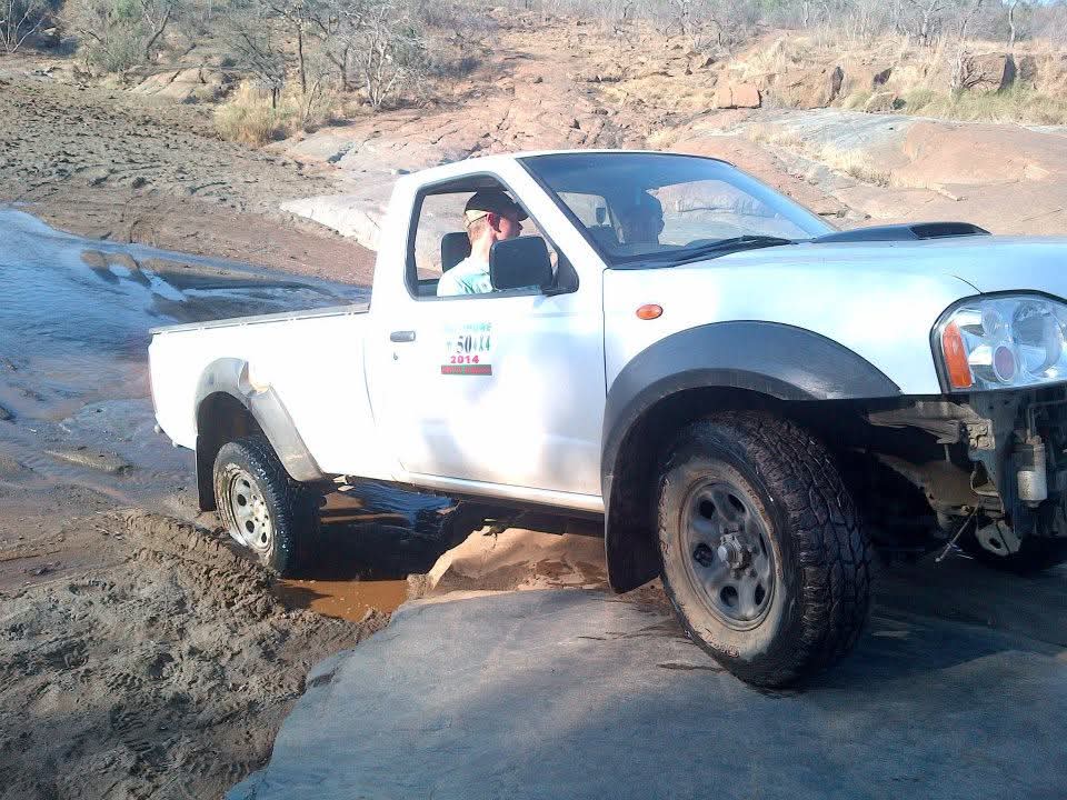A white bakkie crossing a rocky riverbed during a day out