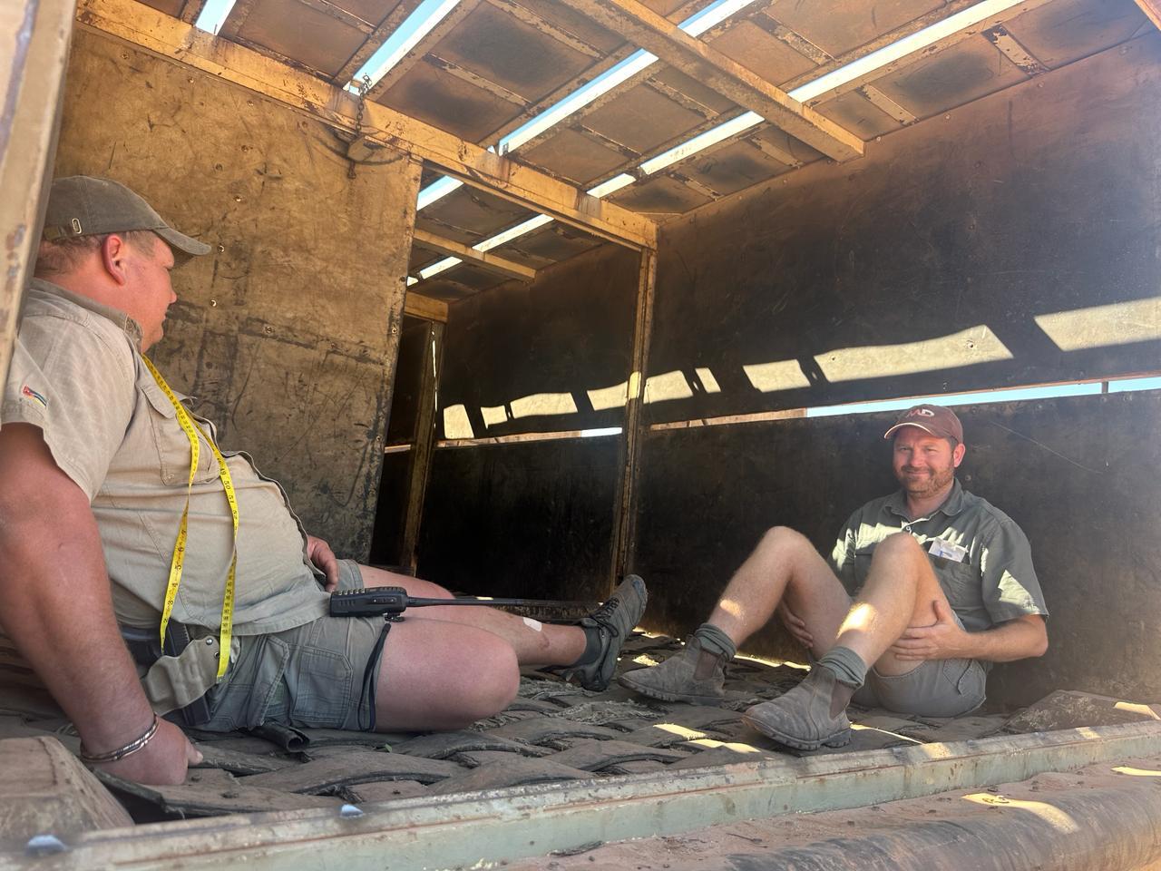 Angelo and a colleague resting inside a game-capture crate after a long operation