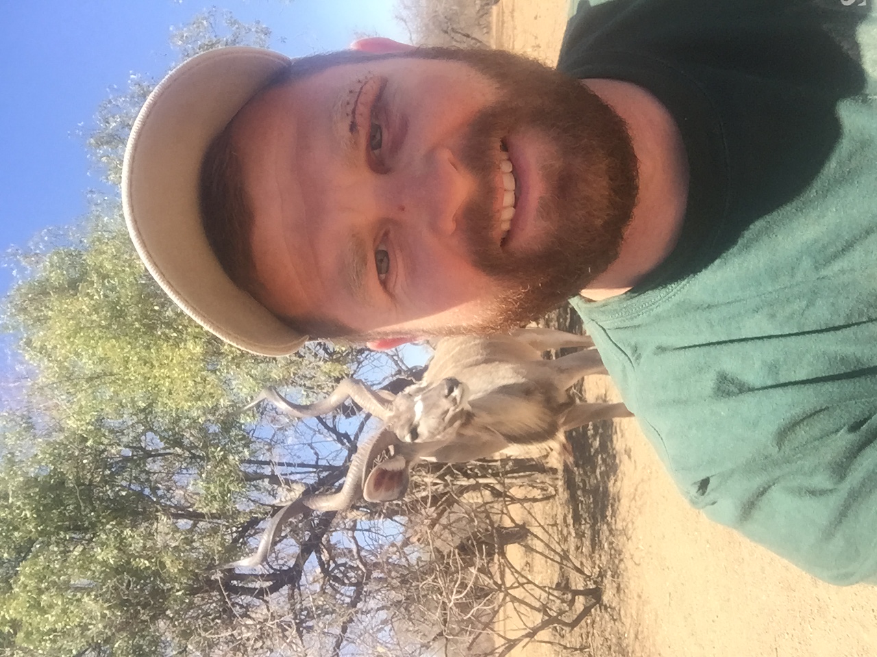 Angelo taking a close selfie with a kudu bull standing behind him