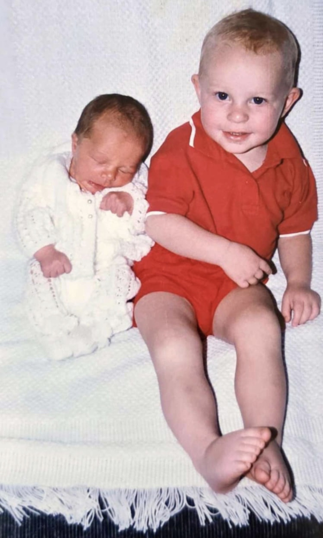 Angelo as a toddler sitting beside his newborn sister
