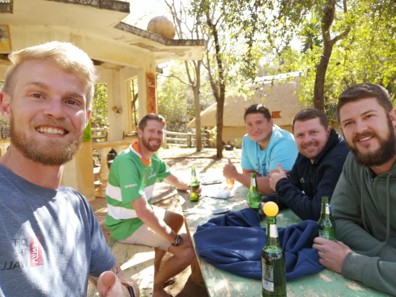 Angelo and friends around a table outside a bush lodge on a sunny day