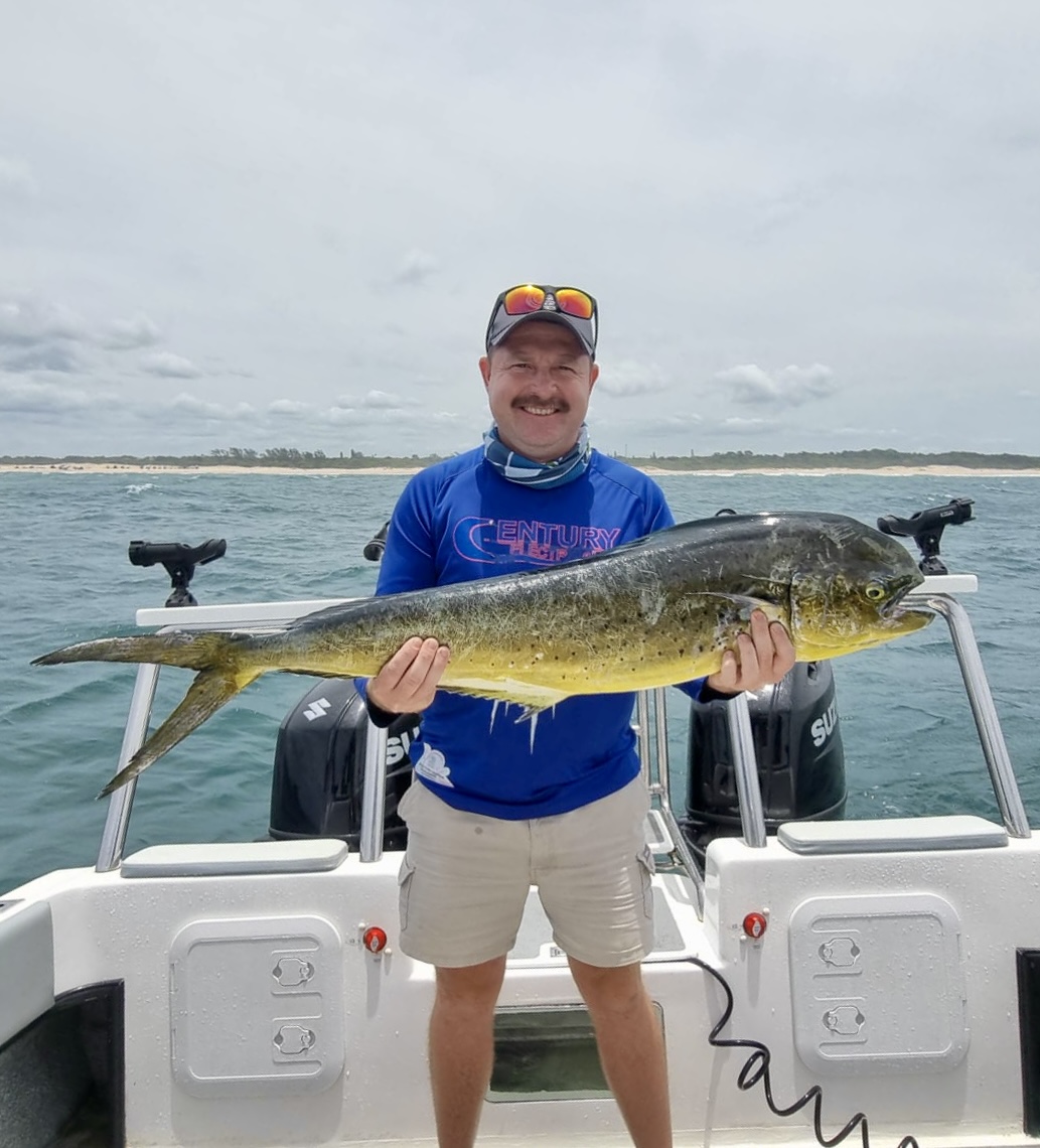 Angelo holding a dorado while standing on a fishing boat