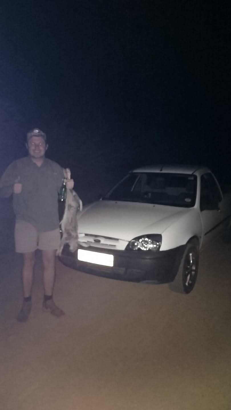 A friend standing beside a white car at night