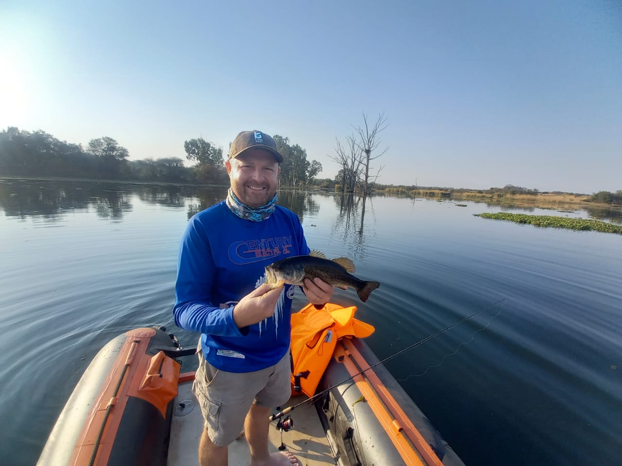 Angelo grinning with a bass in hand on the river at first light