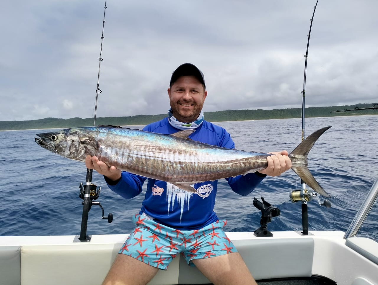Angelo proudly holding a large fish on a sea-fishing boat