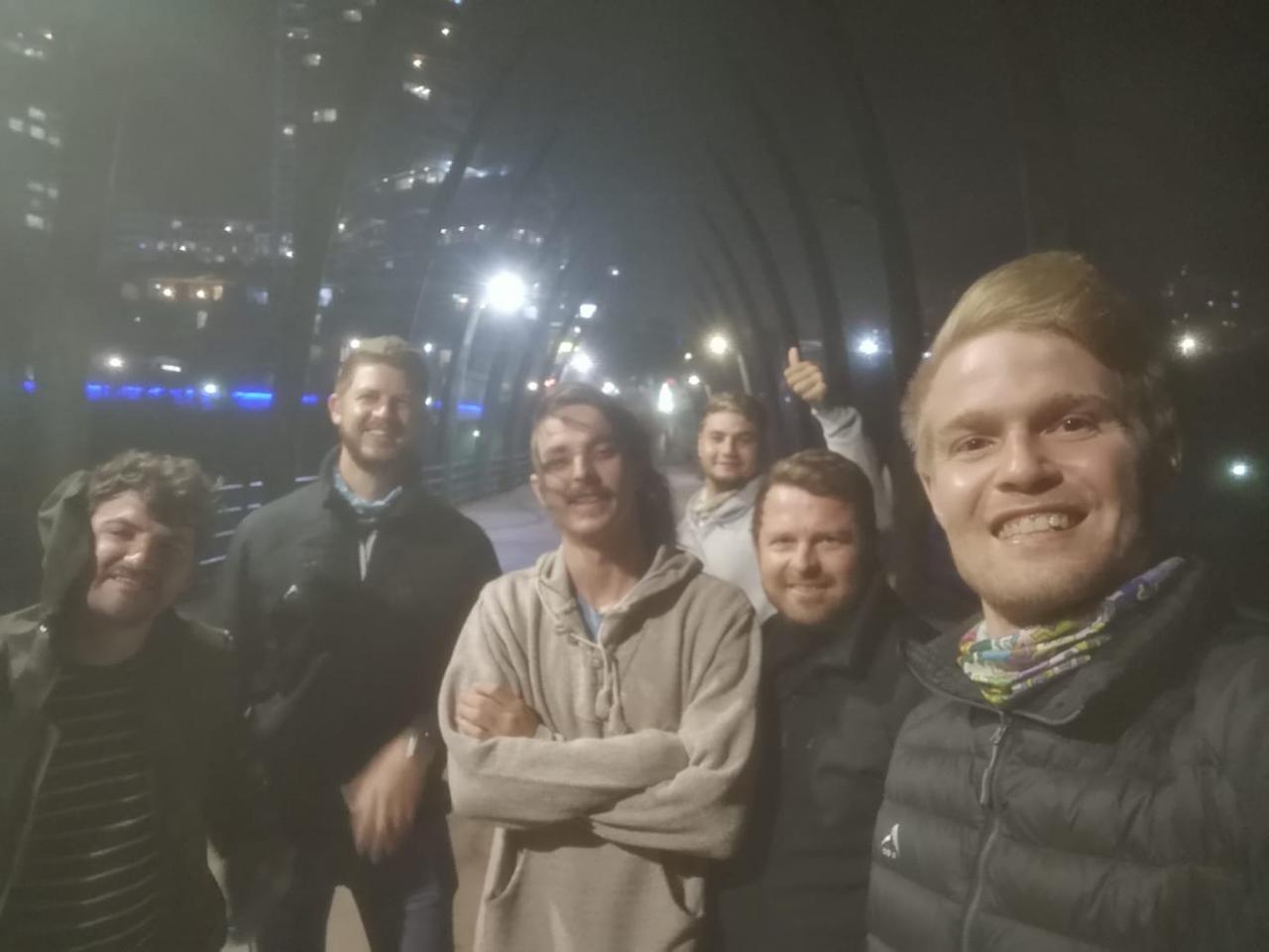 Angelo and friends taking a group selfie on a lit city bridge at night