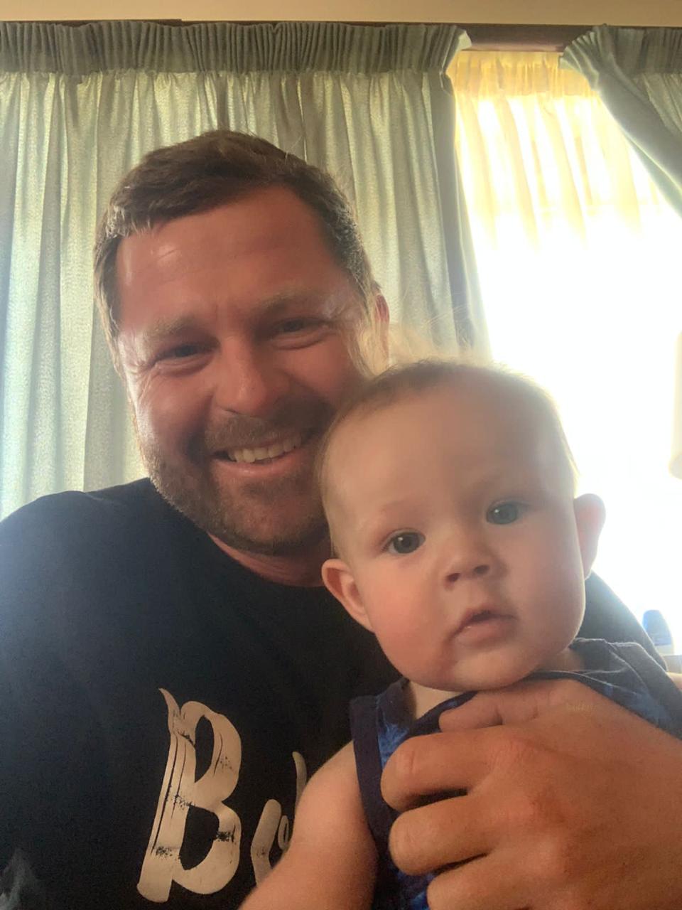 Angelo smiling in a selfie holding a baby