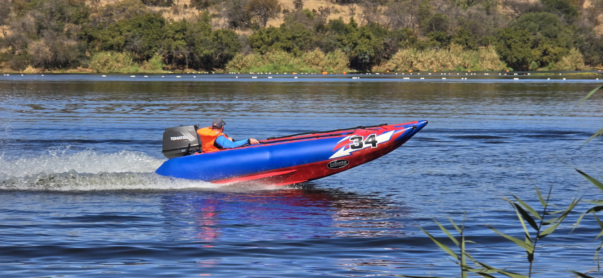A red-and-blue number 34 inflatable boat speeding across the lake