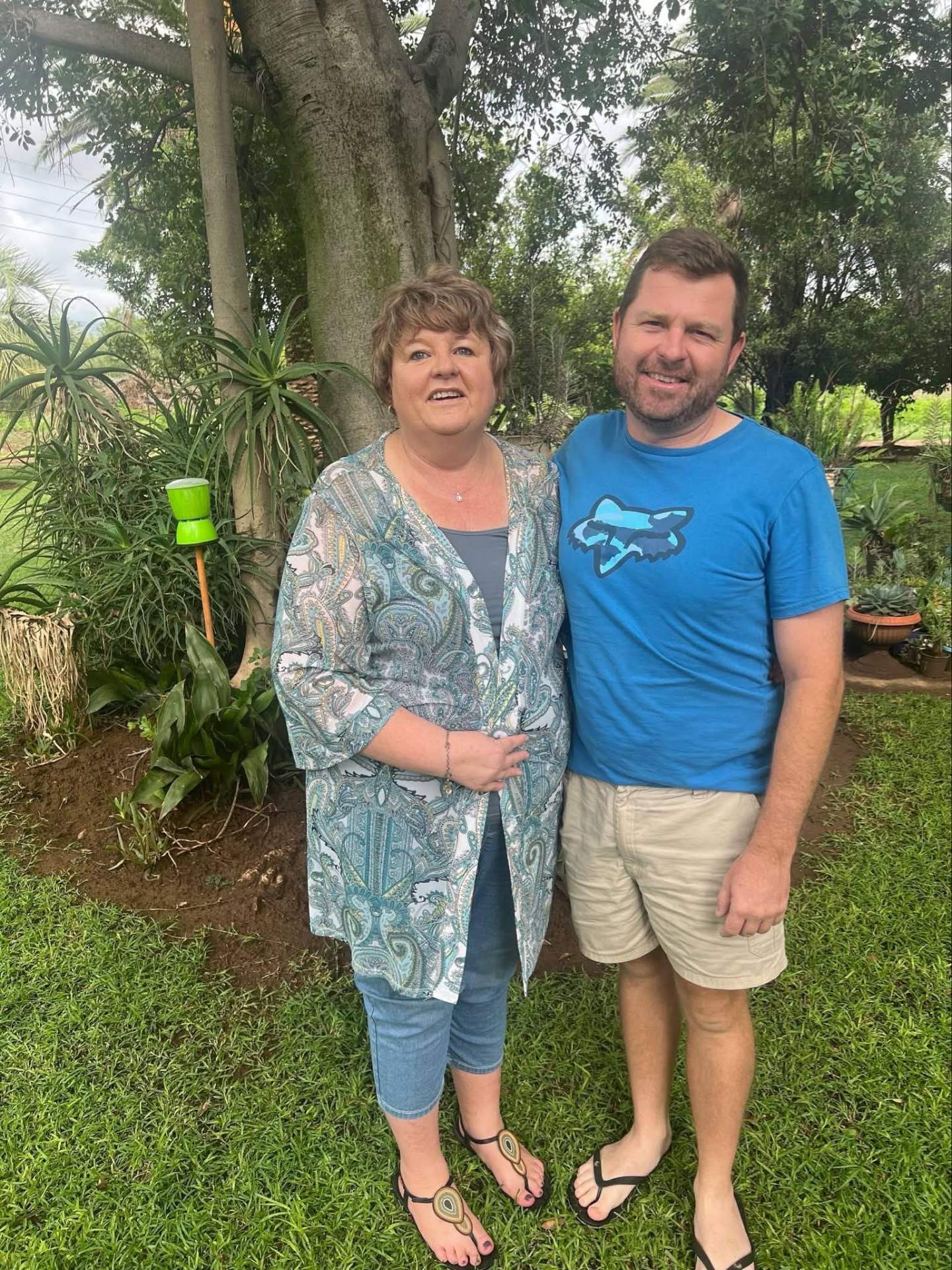 Angelo and his mum smiling together in a green garden