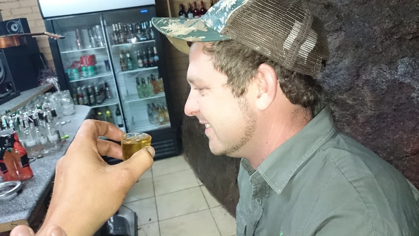 Angelo smiling in a cap while sharing a toast at a bar