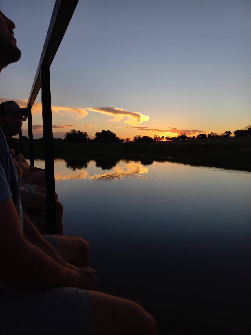 Sunset over a calm river seen from the back of a safari vehicle