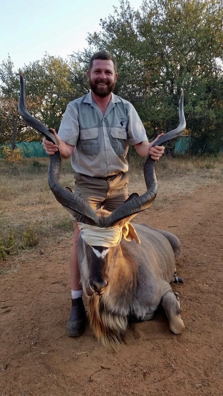 Angelo holding the horns of a large kudu bull at last light