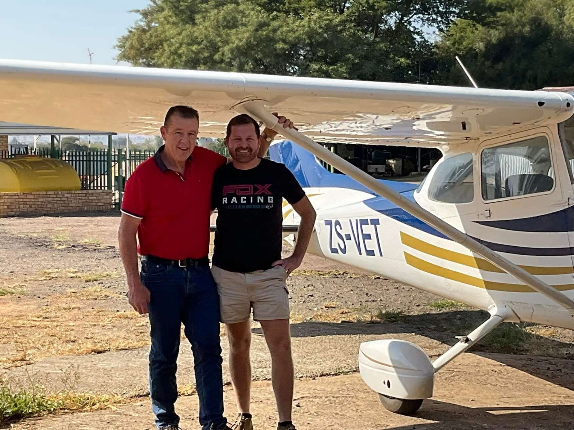 Angelo and another man standing together beside a small aeroplane