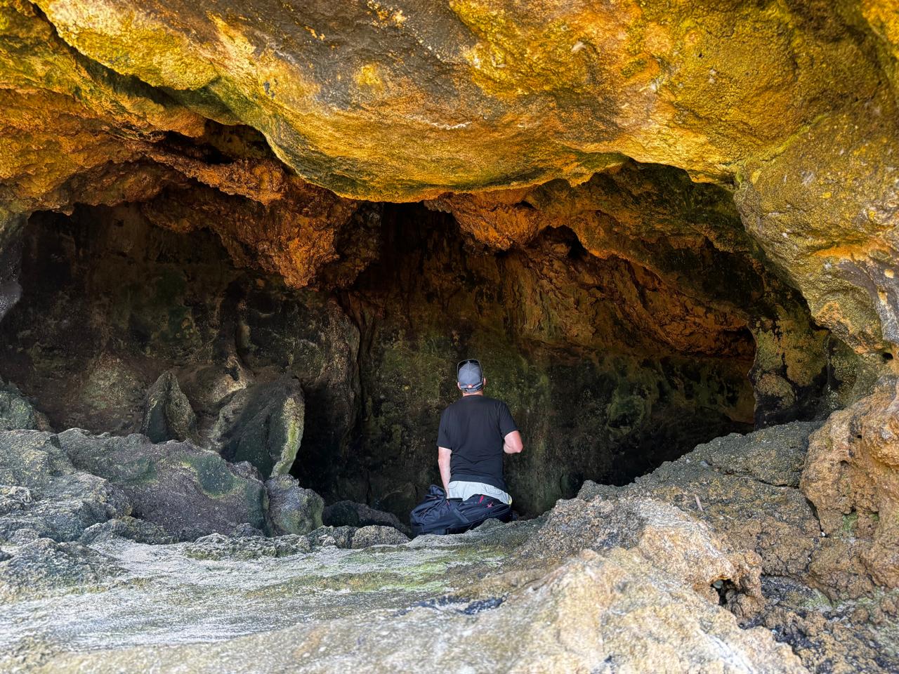 Angelo sitting inside a sea cave lit with warm golden rock