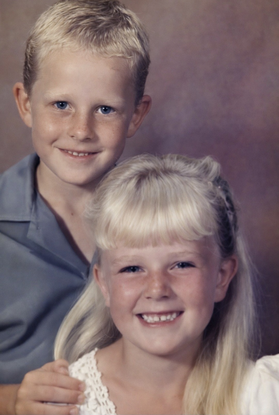 A studio portrait of young Angelo standing behind his little sister