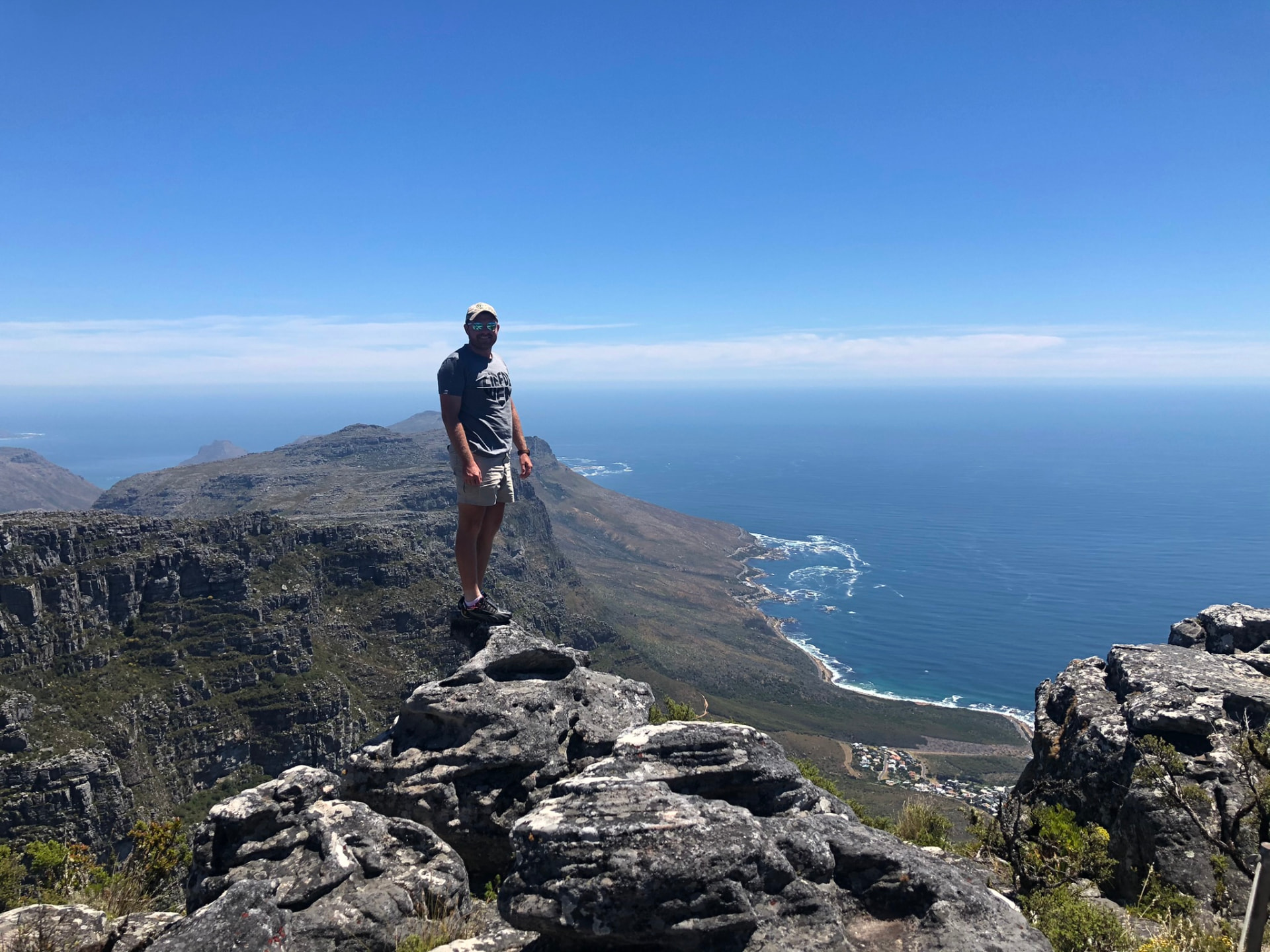 Angelo standing on a rocky summit above the coastline and blue ocean