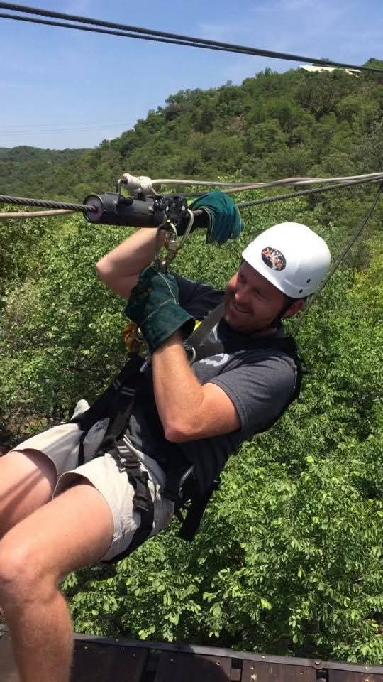 Angelo ziplining above the green bushveld in a white helmet