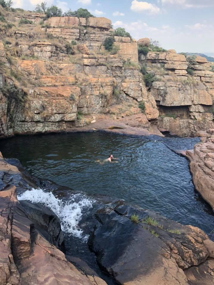 Angelo swimming in a natural rock pool beside a small waterfall