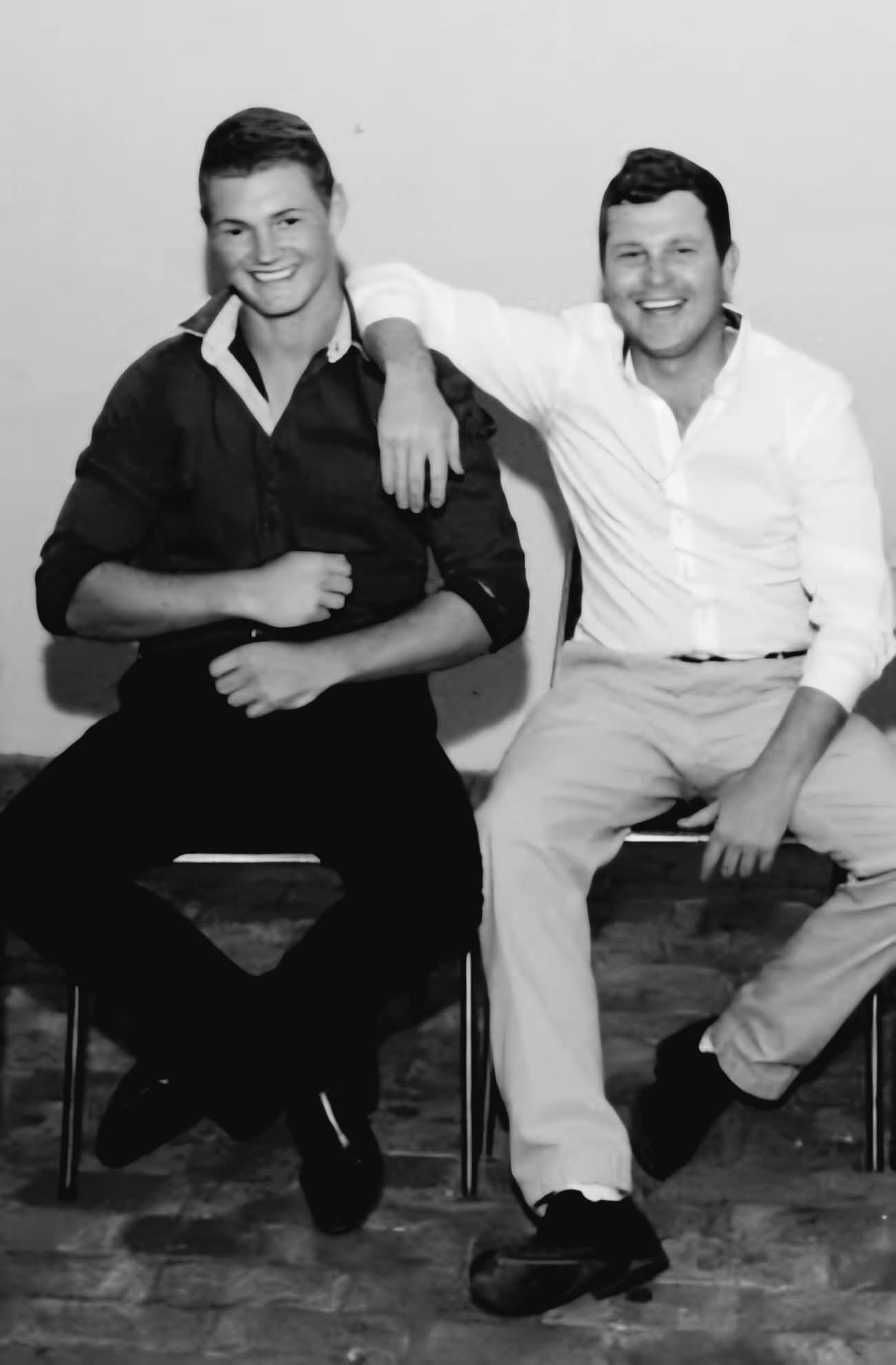 Black-and-white portrait of Angelo sitting beside another man