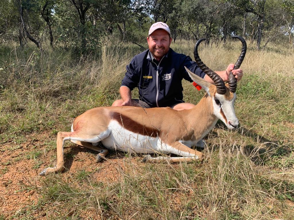 Angelo kneeling beside a springbok ram in the bushveld