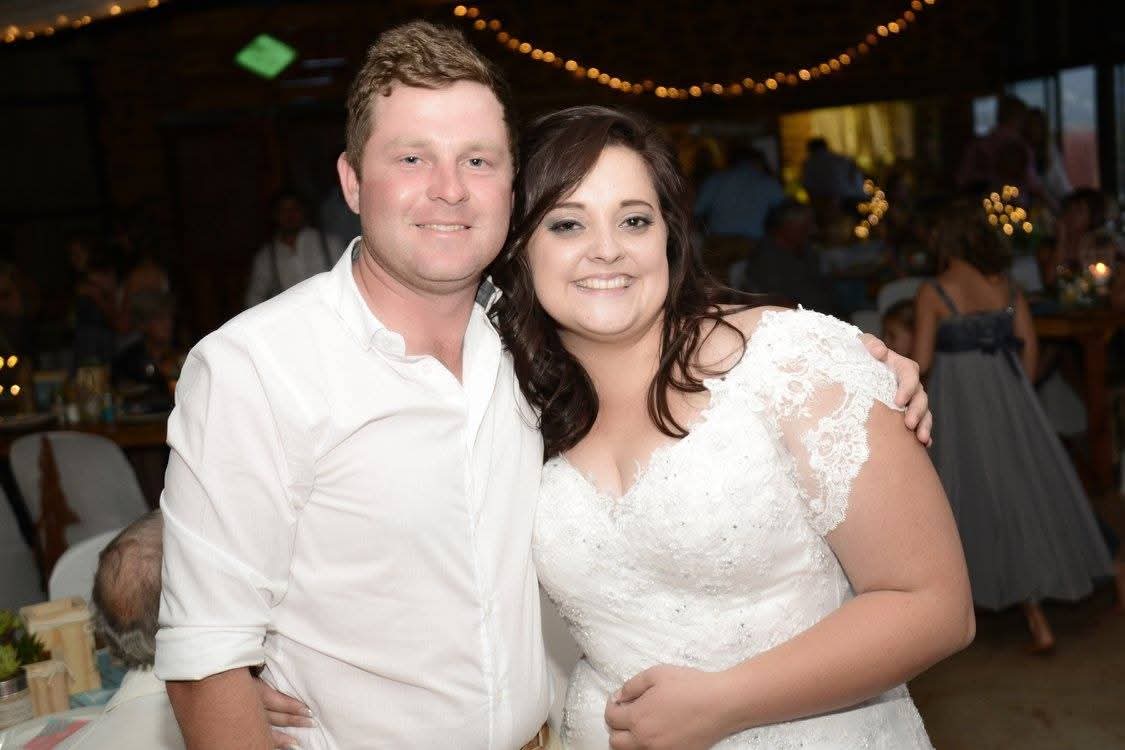 Angelo standing beside a woman in a white dress at a celebration