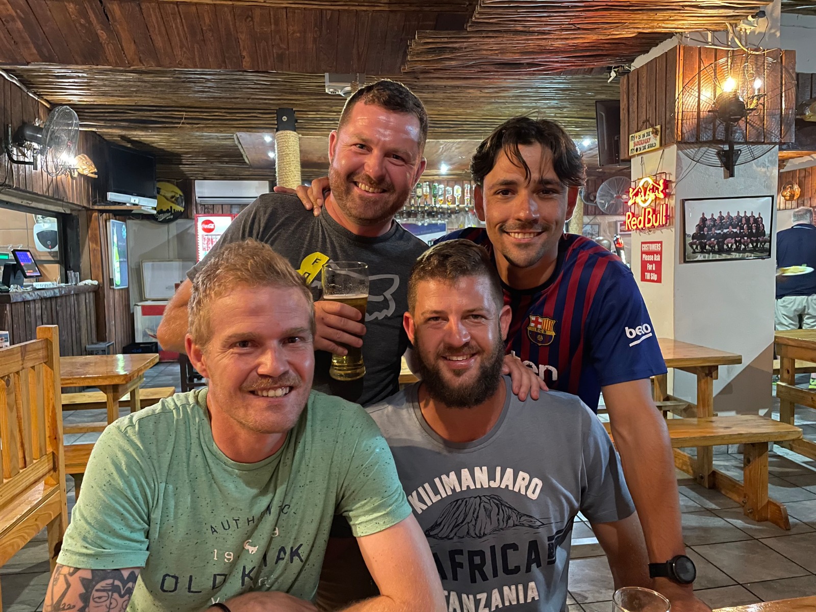 Four friends smiling together at a wooden pub table