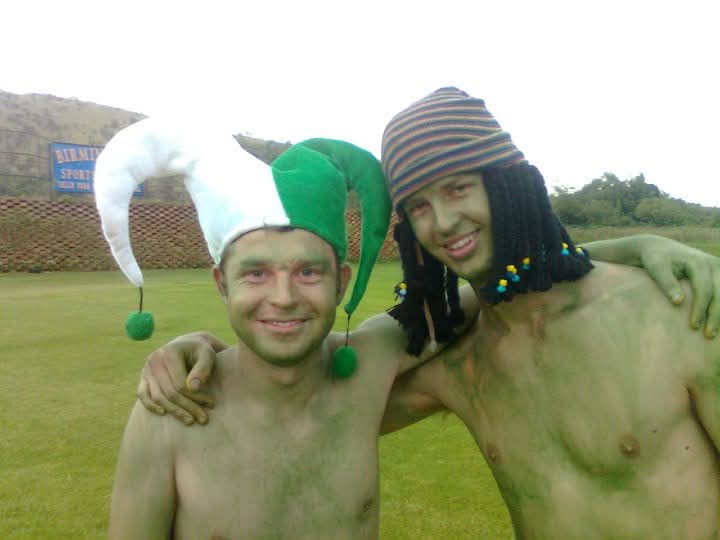 Two friends in face paint and costumes on a sports field