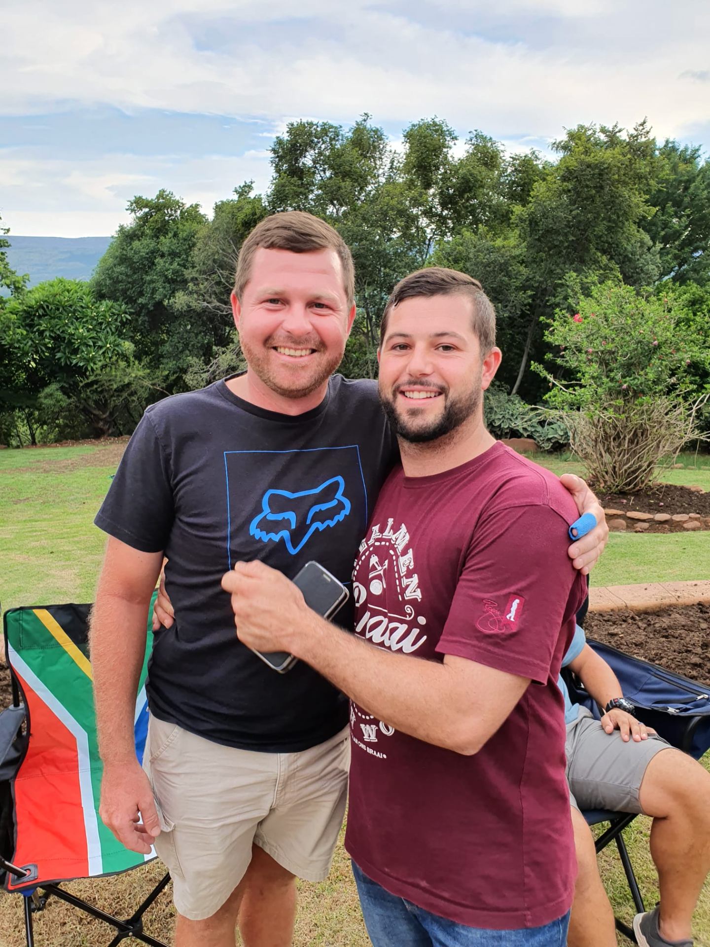Angelo and a friend with their arms around each other at a braai in the garden