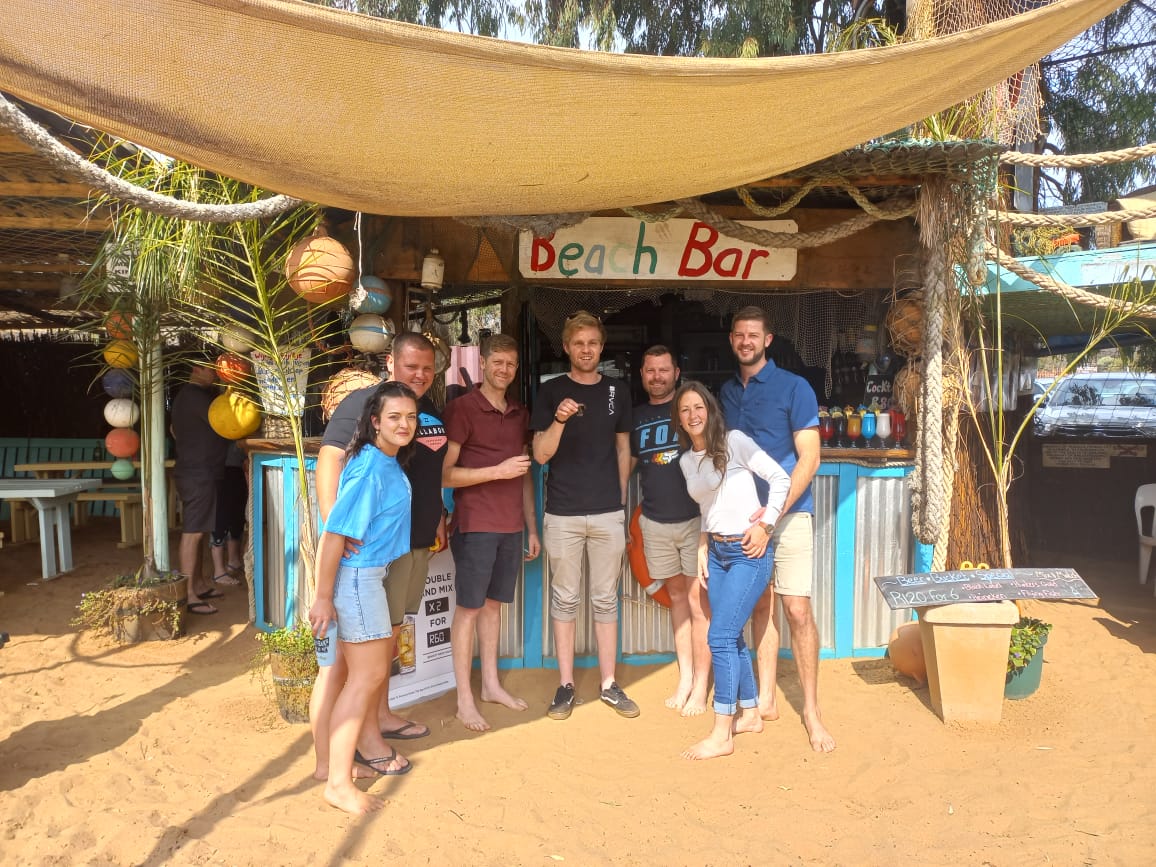 A group of friends standing together in front of a beach bar