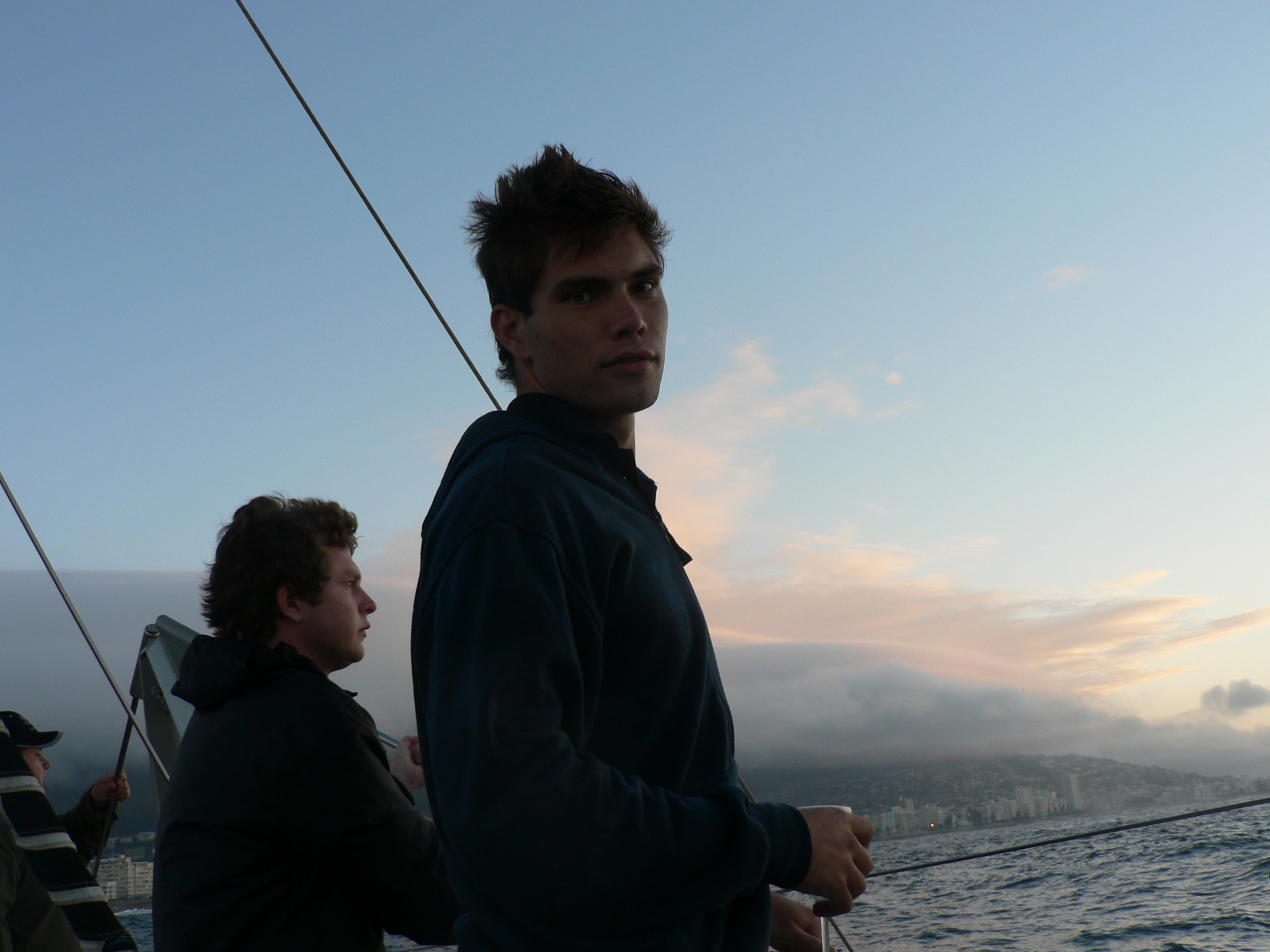Angelo and family aboard a sailing boat at sunset with the coastline behind them