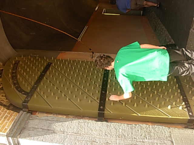 Angelo in a green shirt exploring a large studded doorway