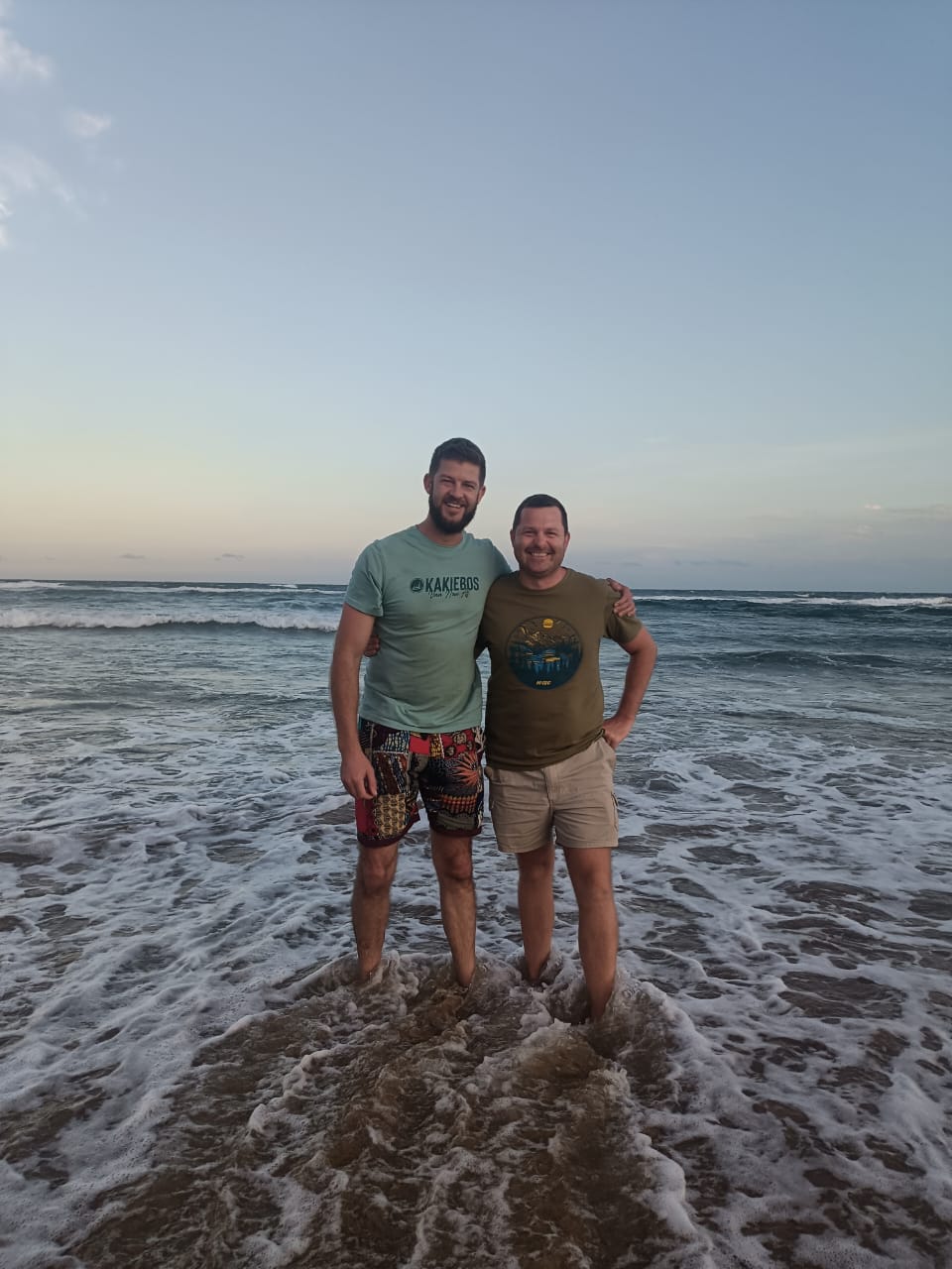 Angelo and his best friend standing in the surf at dusk