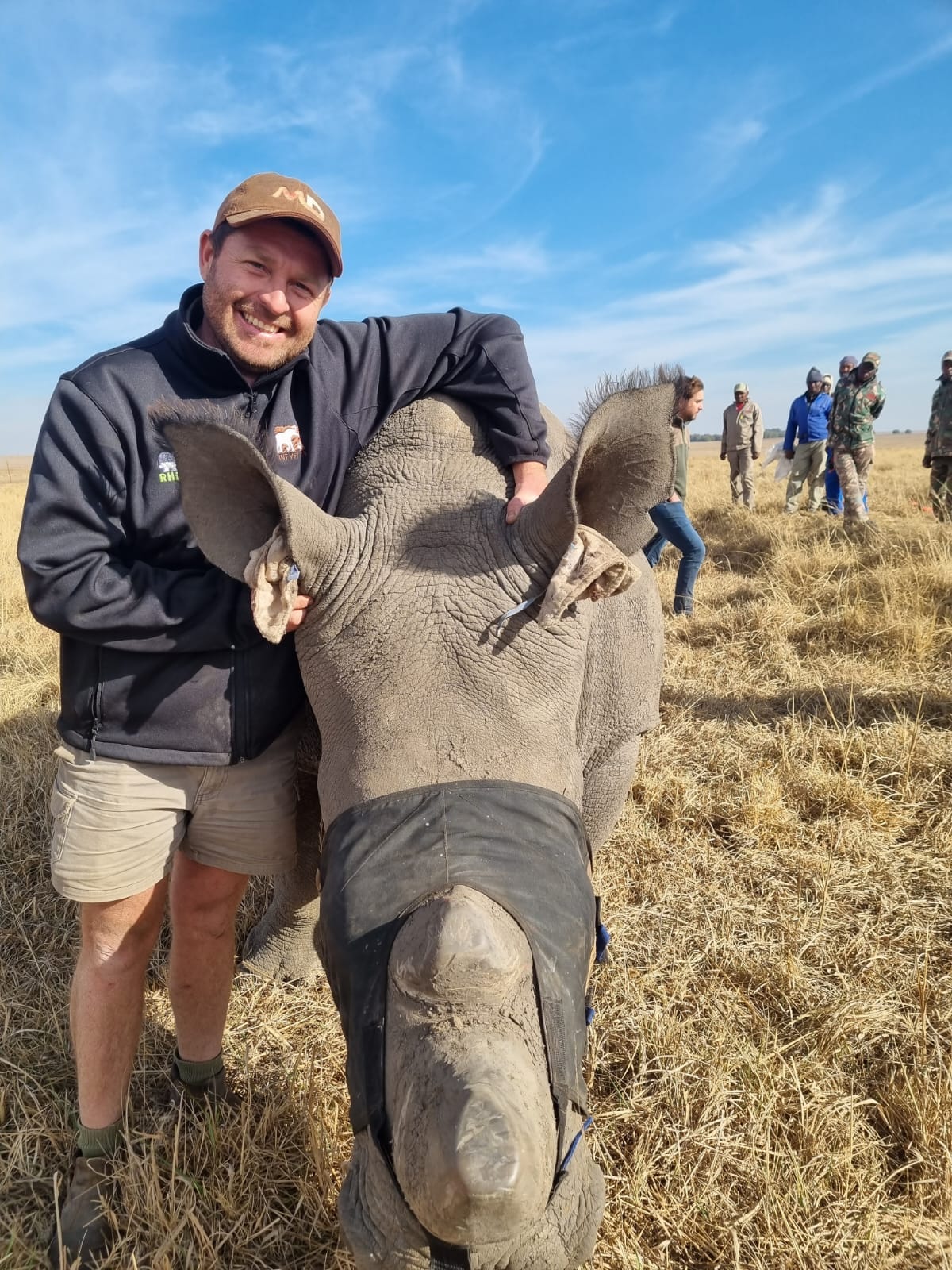 Angelo standing beside a young rhino wearing a protective eye mask