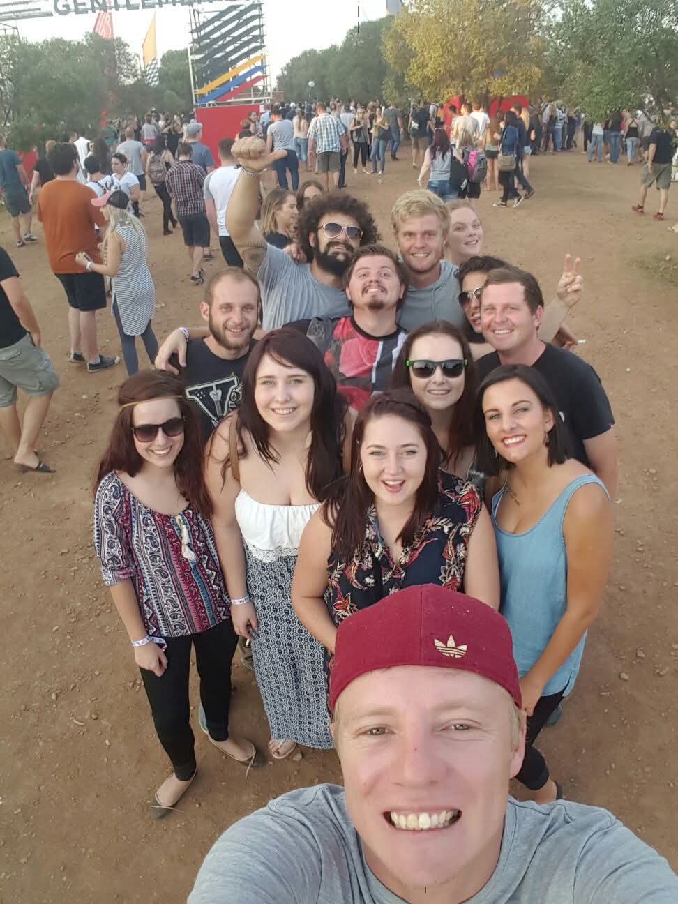 A large group of friends taking a selfie at an outdoor festival